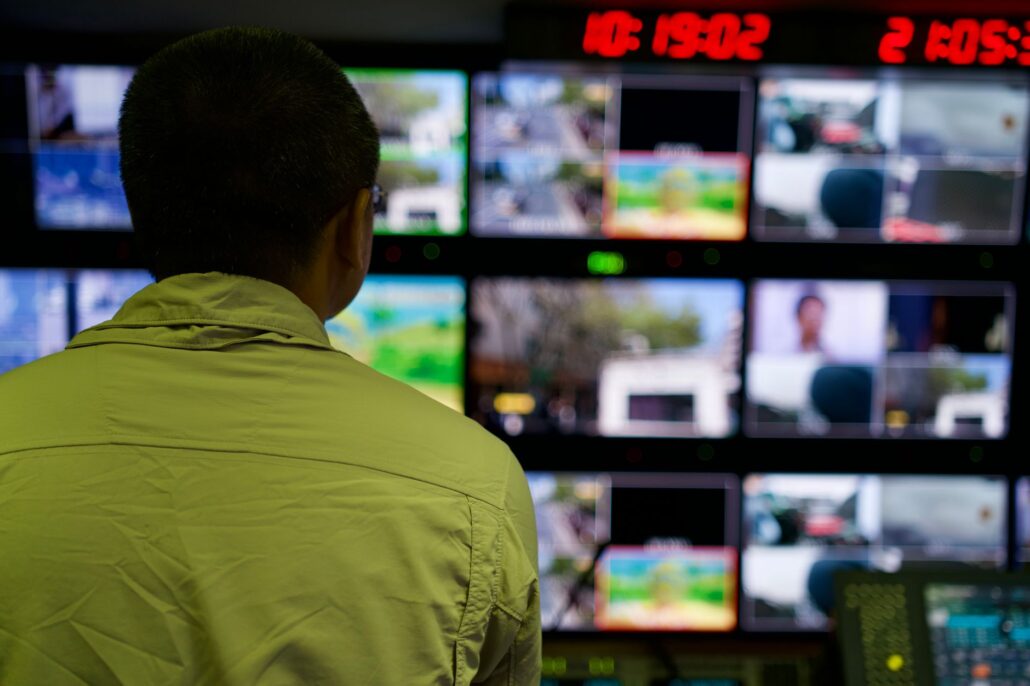Managed IT And Consulting For Confident Business Scaling 2 Man in a control room overseeing multiple monitors displaying various scenes.