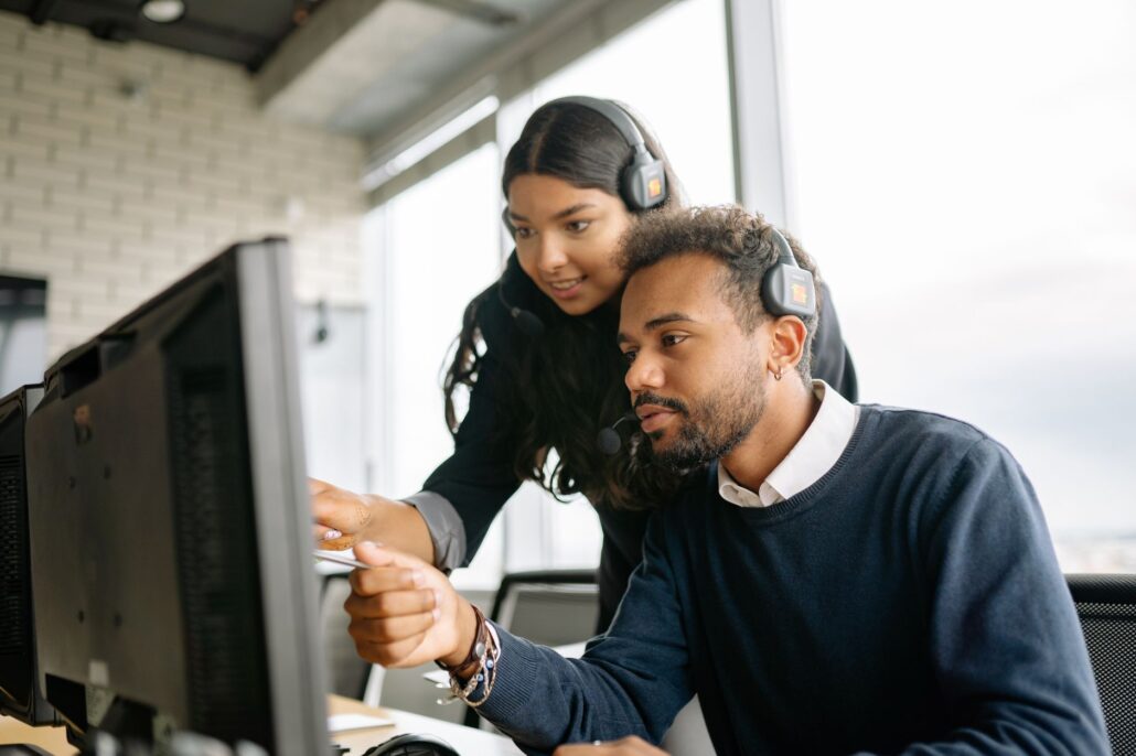 Managed IT And Support For Process-Focused Growing Teams 1 Two call center employees working together with headsets in a modern office setting.