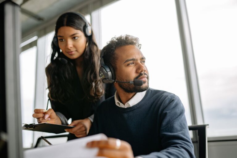 Two professionals working with headsets in a modern office environment, focused on service tasks.